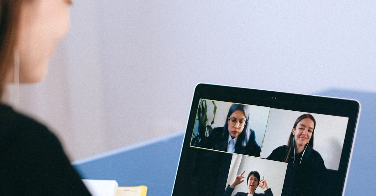 A woman participates in a virtual meeting with colleagues via video call on a laptop.